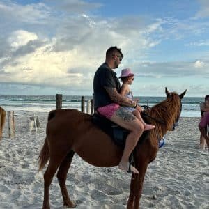 Horse riding on Salalah Beach during sunset with waves and palm trees