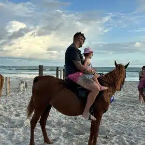 Equitazione sulla spiaggia di Salalah durante il tramonto con onde e palme